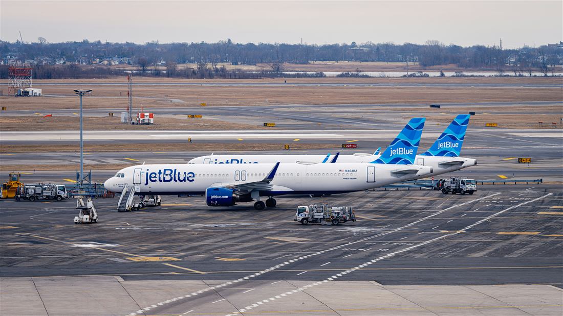 Aircraft at an airport gate with ground service equipment on the apron.